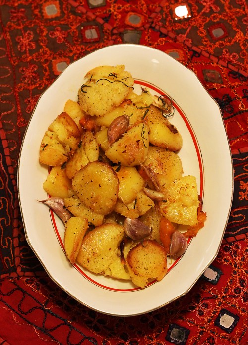 Rapeakuorisiksi paistuneet perunat valkosipulin, appelsiininkuoren ja rosmariinin kanssa.